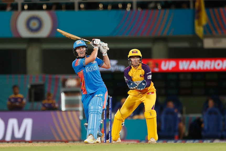 Nat Sciver-Brunt of the Mumbai Indians watches a shot sail away, as UP Warriorz wicketkeeper Alyssa Healy watches on in the WPL.