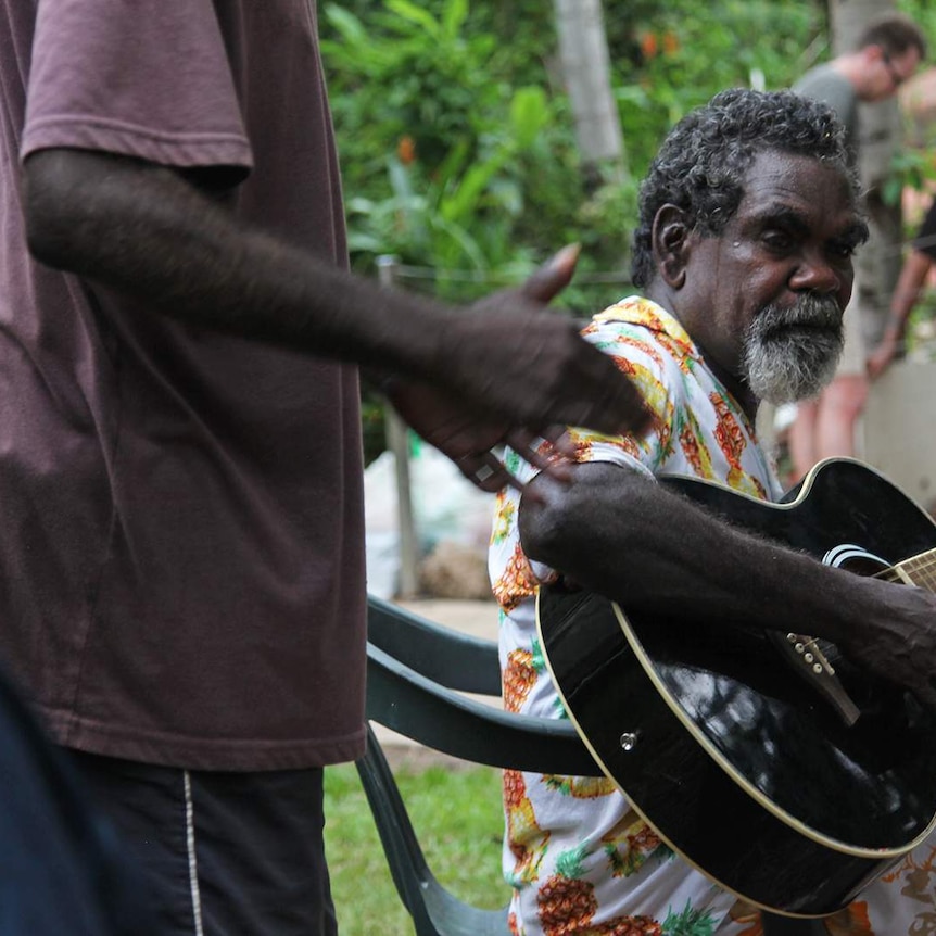 A photo of a long-grasser playing a guitar at Leah Potter's soup kitchen.