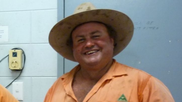 A man in an orange uniform smiles at the camera
