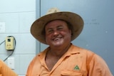 A man in an orange uniform smiles at the camera