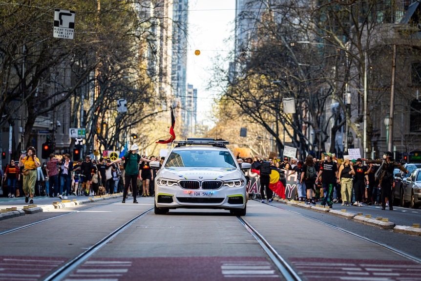 A police car drives down tram tracks in Melbourne during a protest.