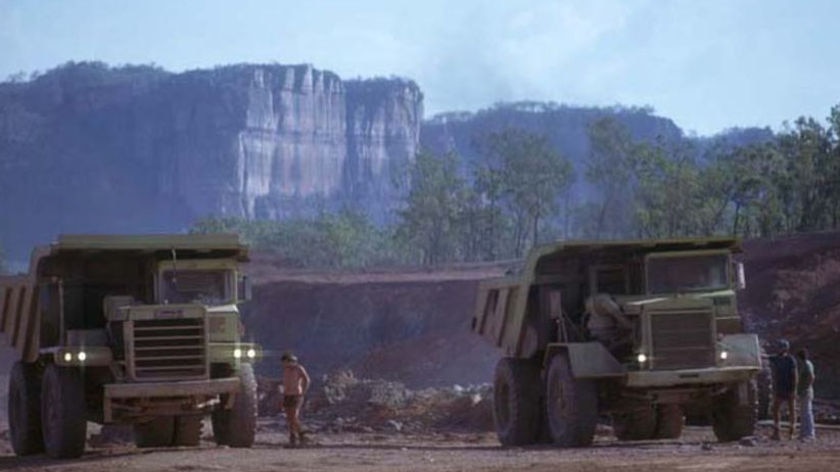 Workers walk between trucks on the Ranger uranium mine.