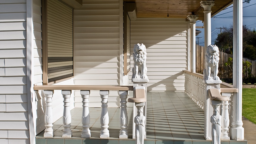 You look at a green-tiled verandah lined by bright white neo-classical columns and two lions and two Grecian statues.