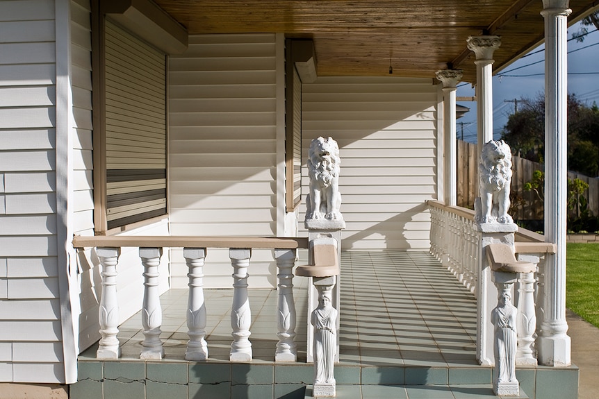 You look at a green-tiled verandah lined by bright white neo-classical columns and two lions and two Grecian statues.