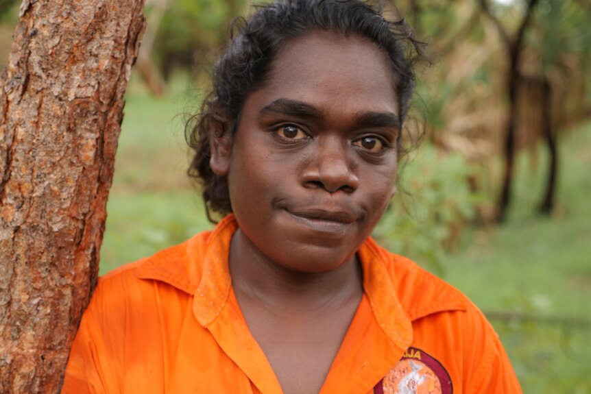 a woman in an orange ranger shirt smiles to the camera