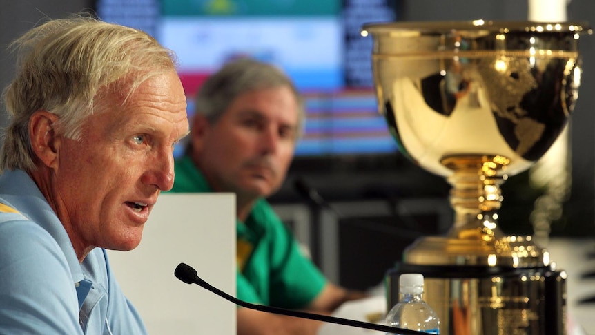 International Team captain Greg Norman talks to the media as US Team captain Fred Couples looks on.
