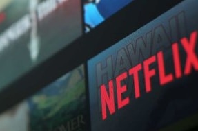 Czerwone logo Netflix na ekranie z innymi programami.