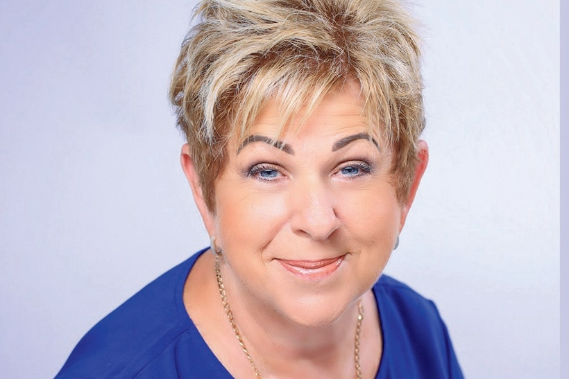 Corporate headshot of woman in blue top.