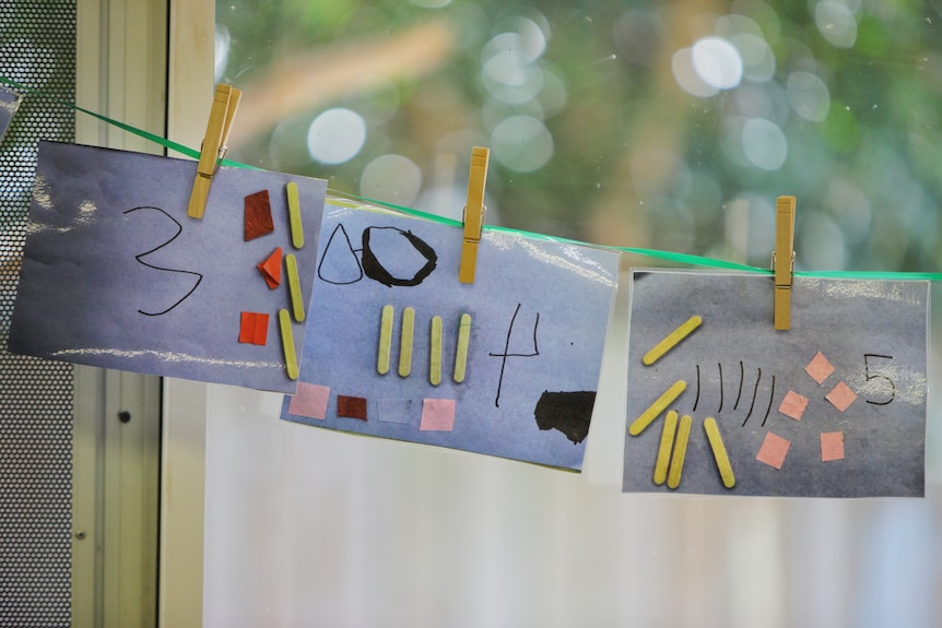 Three pictures of children's artwork hanging on a string. 