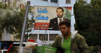 A man on a motorcycle rides past a poster of outgoing prime minister saad hariri