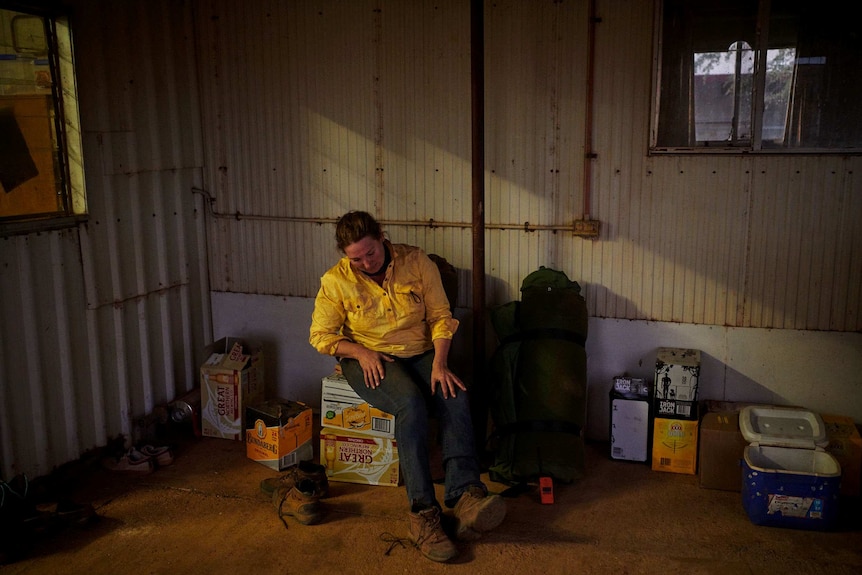 Jane Sale site on cartons of beer and removes her work boots