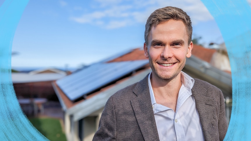 Head and shoulders image of a man in a casual shirt and suit jacket smiling with a house in the background.