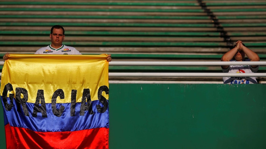A fans in the stands of Arena Conda stadium holds a flag reading "gracias".