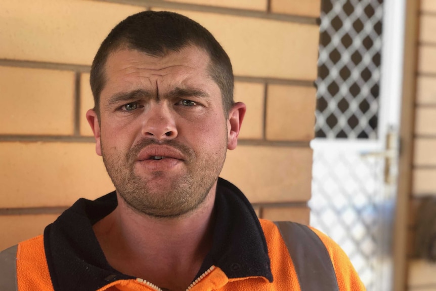 A head shot of Indigenous man Brendan O'Connor, with the brick exterior of his home in soft focus in the background.