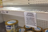 A sign on supermarket on a near empty supermarket shelf restricts the sale of baby formula to 4 cans