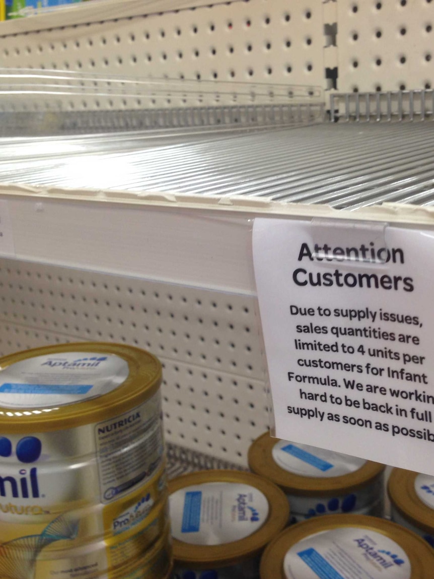 A sign on supermarket on a near empty supermarket shelf restricts the sale of baby formula to 4 cans