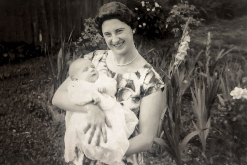 A black and white photo of a young woman holding a baby