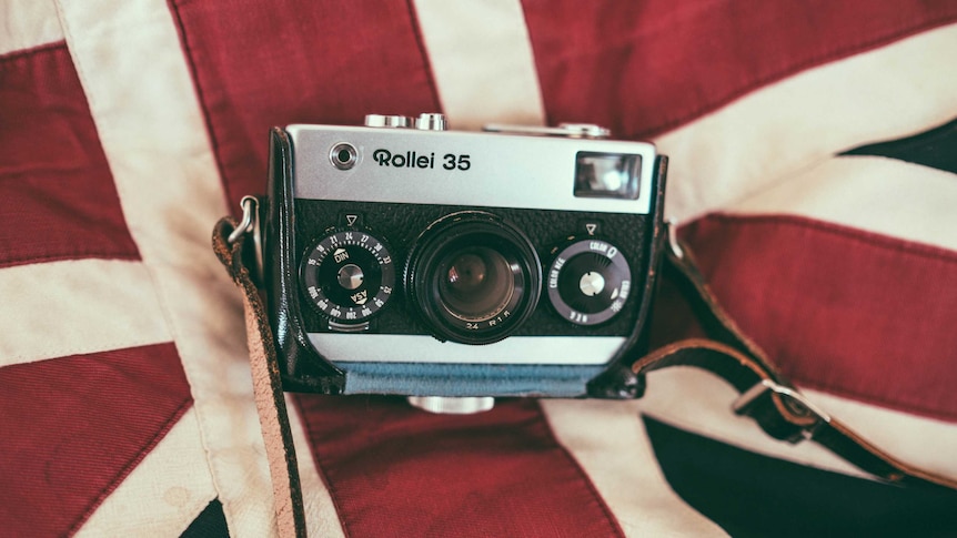 A photograph of an older style Rollei 35 camera sitting on top of a fabric Union Jack.