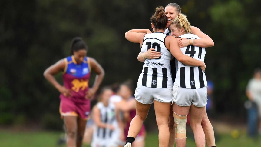 Collingwood celebrates a win over Brisbane, with the Lions' Sabrina Frederick-Traub in background.