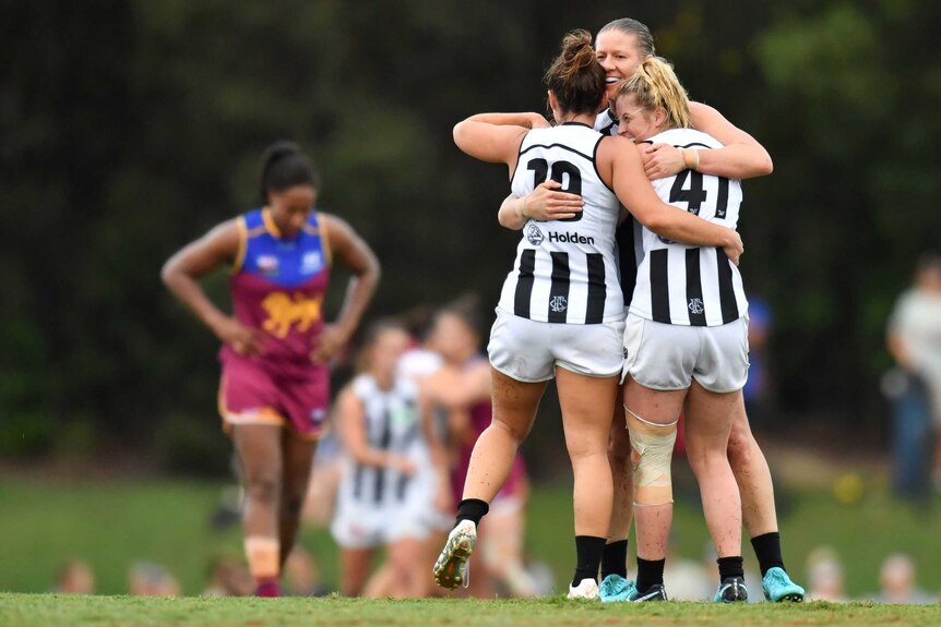 Collingwood celebrates a win over Brisbane, with the Lions' Sabrina Frederick-Traub in background.