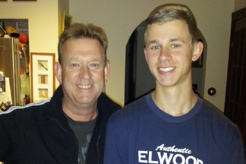 Murray Kinnane standing next to his son inside a house.