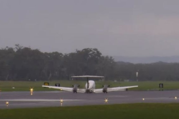 A plane lands without its undercarriage down on a runway.