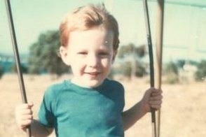 Historic photo of a boy on a swing in a rural setting.