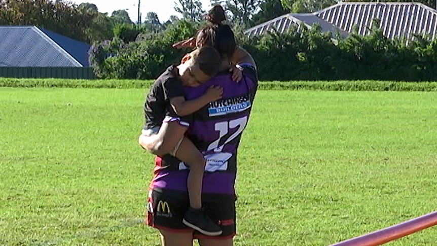 One of the Toowoomba women's players holds her child on the sideline.