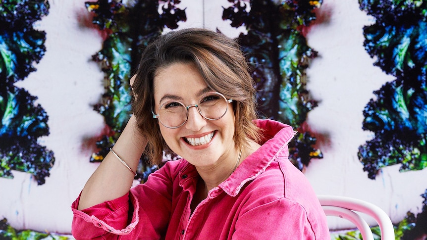 A woman in a pink jacket grins at the camera.