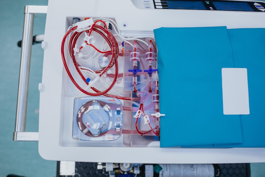 Red tubes and vials on a white tray, with a folded green cloth on the side.