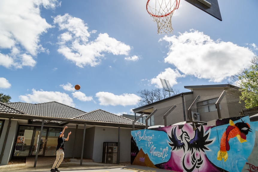 A basketball thrown by Eddie Fejo is mid-air as it heads towards the hoop on a court at the school.