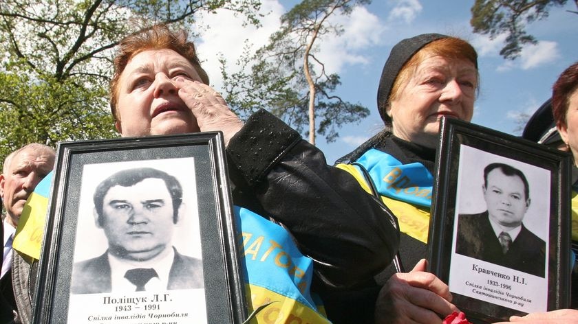 Women hold pictures of their dead husbands during the commemoration ceremony at Chernobyl's memorial