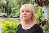 Middle aged woman with blond hair, wearing a black shirt