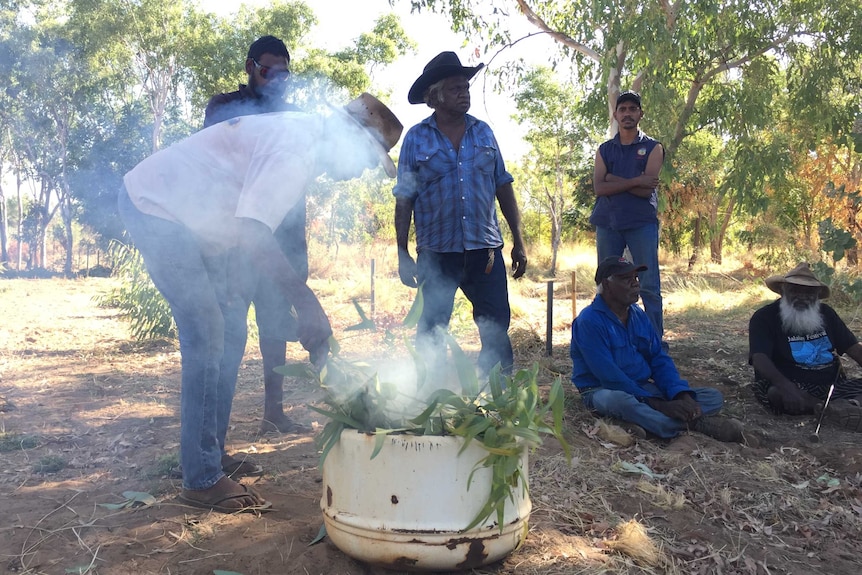 Indigenous elders performing a smoking ceremony at the Fitzroy River cemetery.
