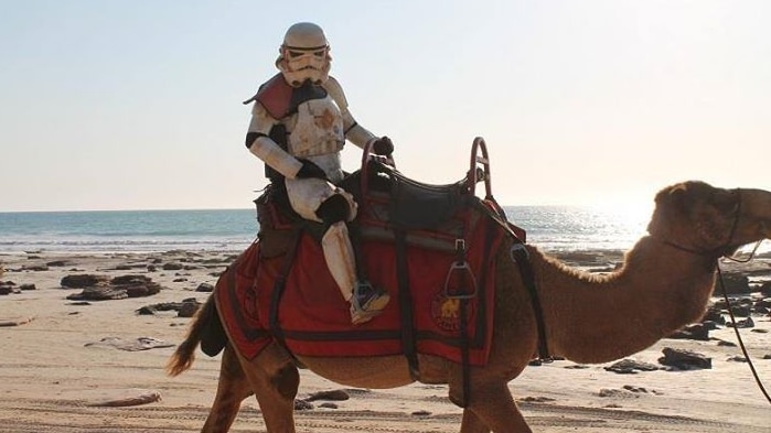 Scott loxley, dressed as a storm trooper, rides a camel on Cable Beach in Broome.