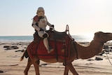 Scott loxley, dressed as a storm trooper, rides a camel on Cable Beach in Broome.