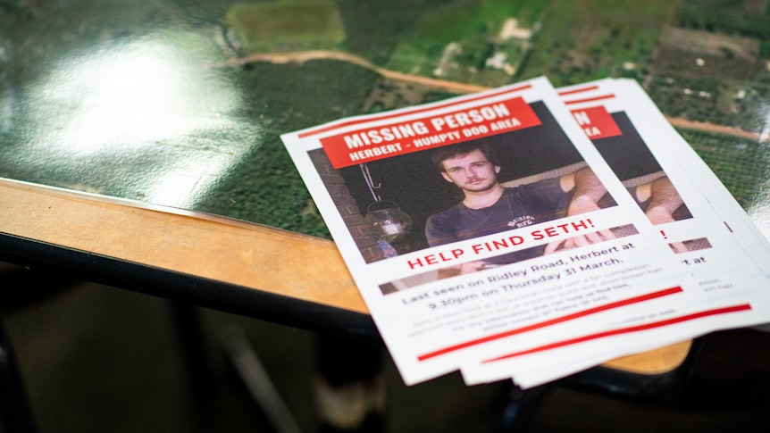 A stack of missing person posters on a table, showing a photo of missing teenager Seth Puckridge. 