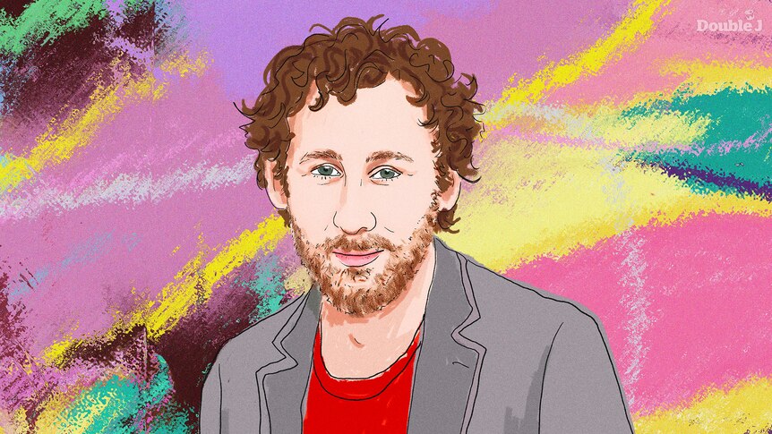 A portrait of musician Ben Lee. He wears a red shirt and brown jacket and has brown hair and a beard. 