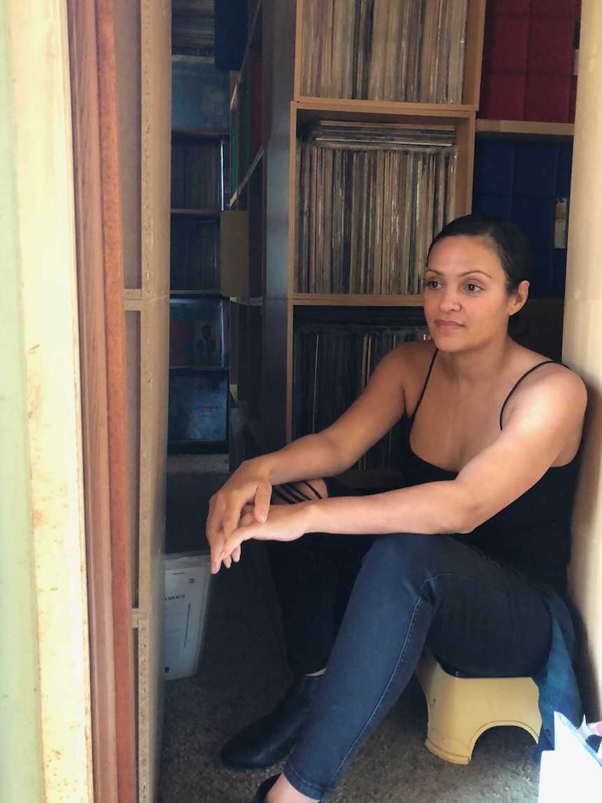 Natalie Perkins sits next to a stack of albums pondering their future.