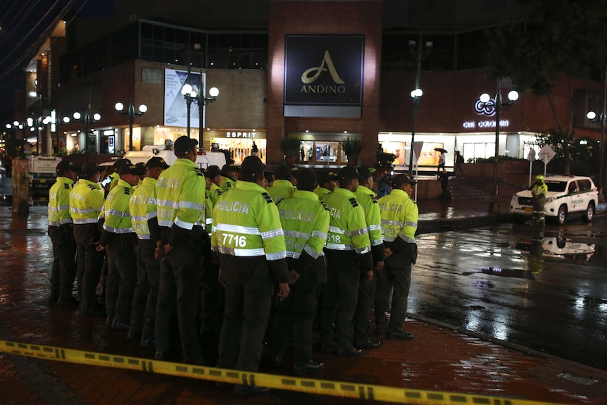 Police officers wearing fluorescent jackets under the Centro Andino shopping mall sign,