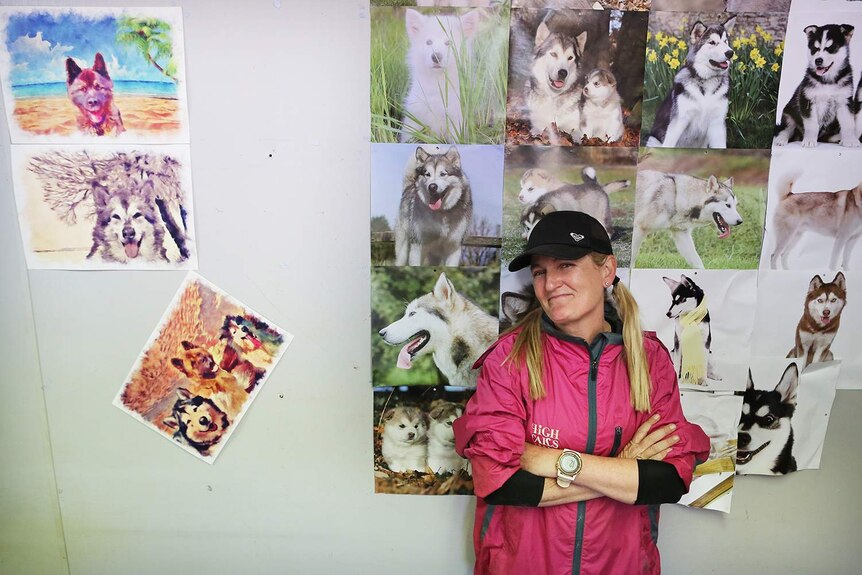 Janelle Wyatt leaning up against a wall of dog pictures.