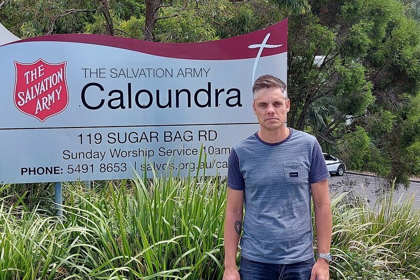 Calvin Taylor stands next to Salvation Army sign looking serious