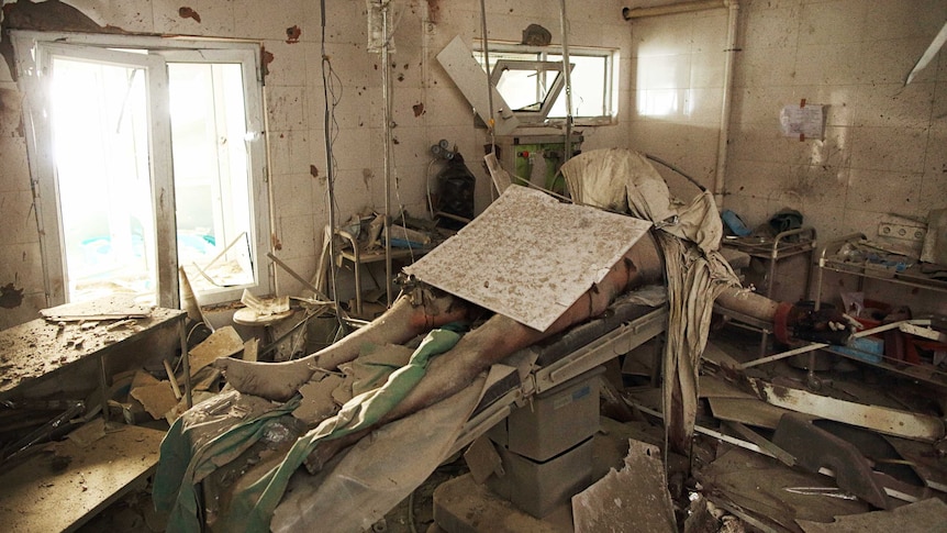 A man lying underneath rubble on an operating table.