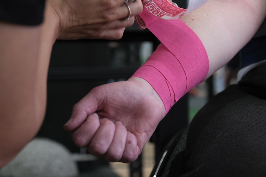 Ainslee Hooper gets pink tape around her arm.