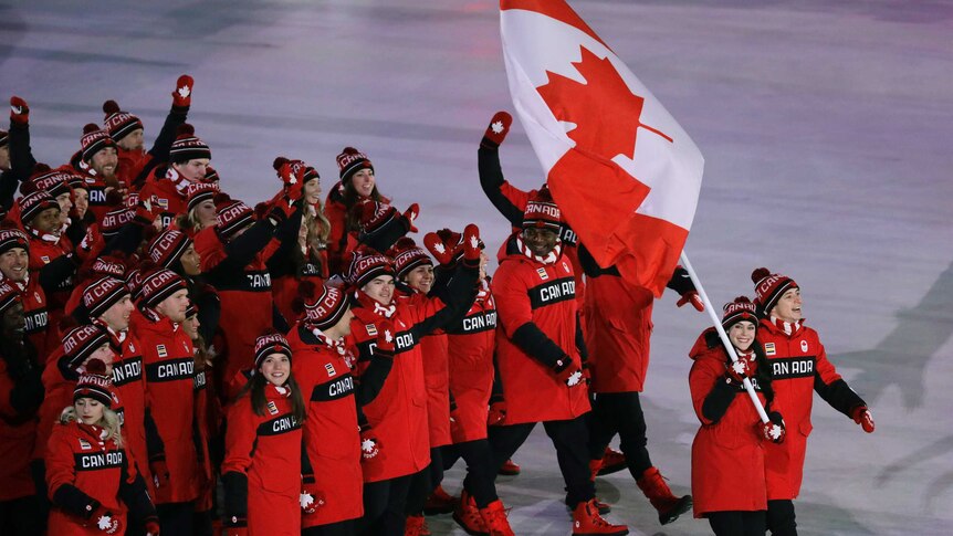 Tessa Virtue walking with Scott Moir carries the flag of Canada in the Pyeongchang opening ceremony.