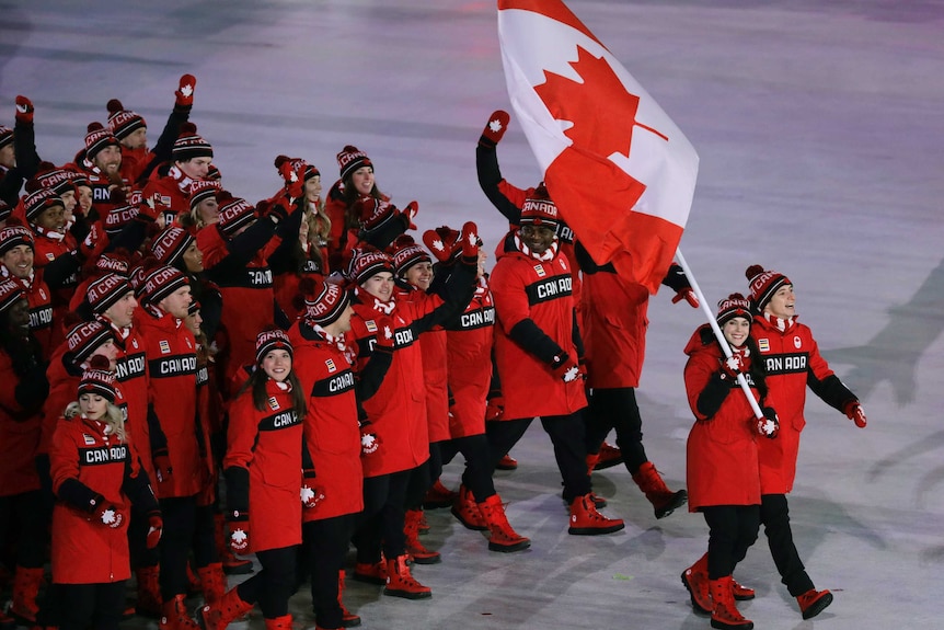 Tessa Virtue walking with Scott Moir carries the flag of Canada in the Pyeongchang opening ceremony.