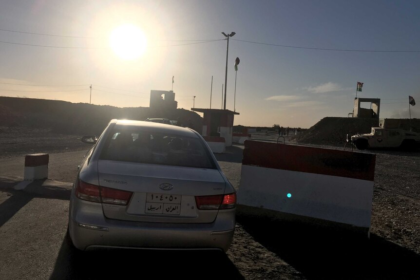 An Iraqi family's car passes the checkpoint in Makhmour, Iraq, on the way back to their village.