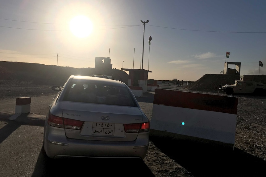 An Iraqi family's car passes the checkpoint in Makhmour, Iraq, on the way back to their village.