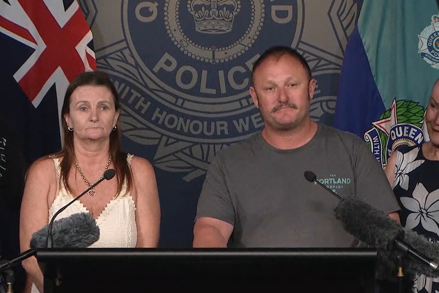 A middle-aged man and middle-aged woman stand at a lectern at a Police media conference