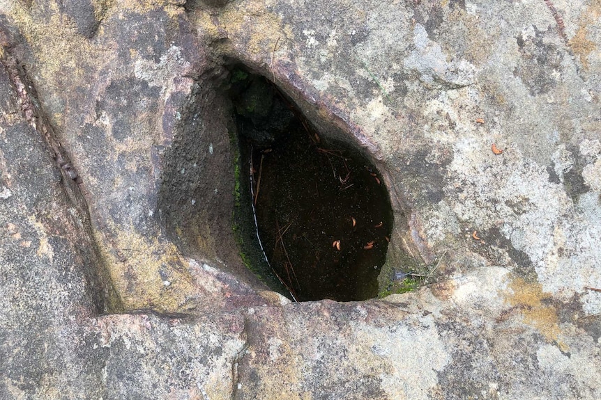 A small indentation in the rock, made by traditional owners, containing water